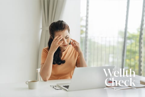 Burnt out woman looking at computer while rubbing her temple