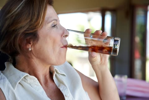 Attractive mature woman drinking soda