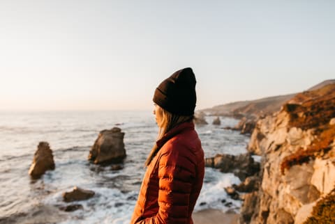 Woman looking out enjoying the view of the Pacific Ocean off of California’s central coast. Woman looking out enjoying the view of the Pacific Ocean off of California’s central coast.
