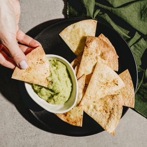 Hand Dipping Tortilla Chip into Guacamole Hand Dipping Tortilla Chip into Guacamole
