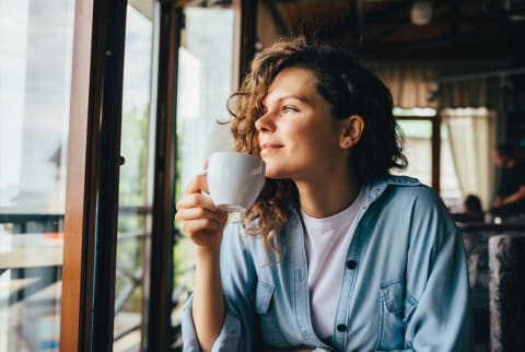 woman drinking coffee looking out window woman drinking coffee looking out window