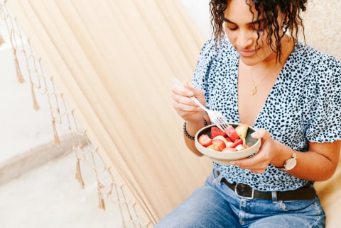 Woman Eating Fruit While Sitting In A Hammock Woman Eating Fruit While Sitting In A Hammock