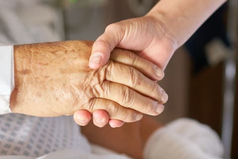 Health practitioner holding the hand of an elderly patient