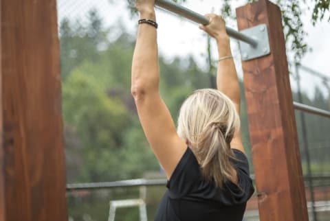 Woman doing a pull up out in an outdoor gym Woman doing a pull up out in an outdoor gym