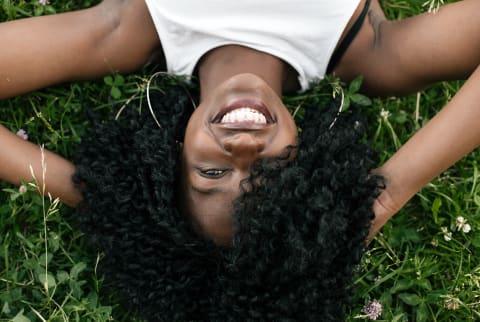 girl with curls laying down in the grass girl with curls laying down in the grass