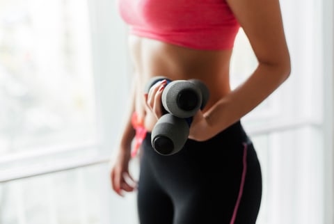 Cropped image of a woman holding fitness dumbbells. Cropped image of a woman holding fitness dumbbells.