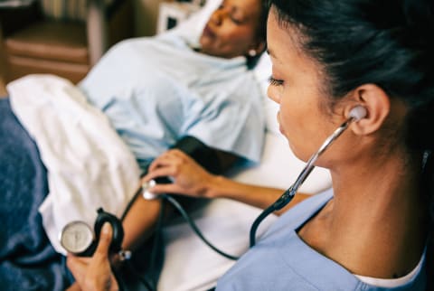 Hospital: Nurse Takes Blood Pressure Reading From Patient In Bed Hospital: Nurse Takes Blood Pressure Reading From Patient In Bed